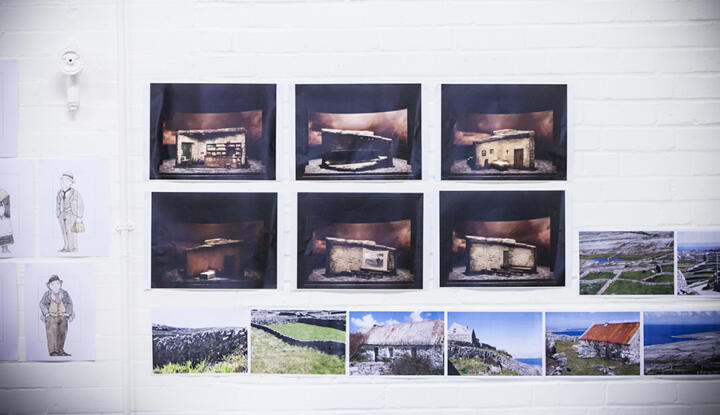 photographs on a wall of countryside and a stone house